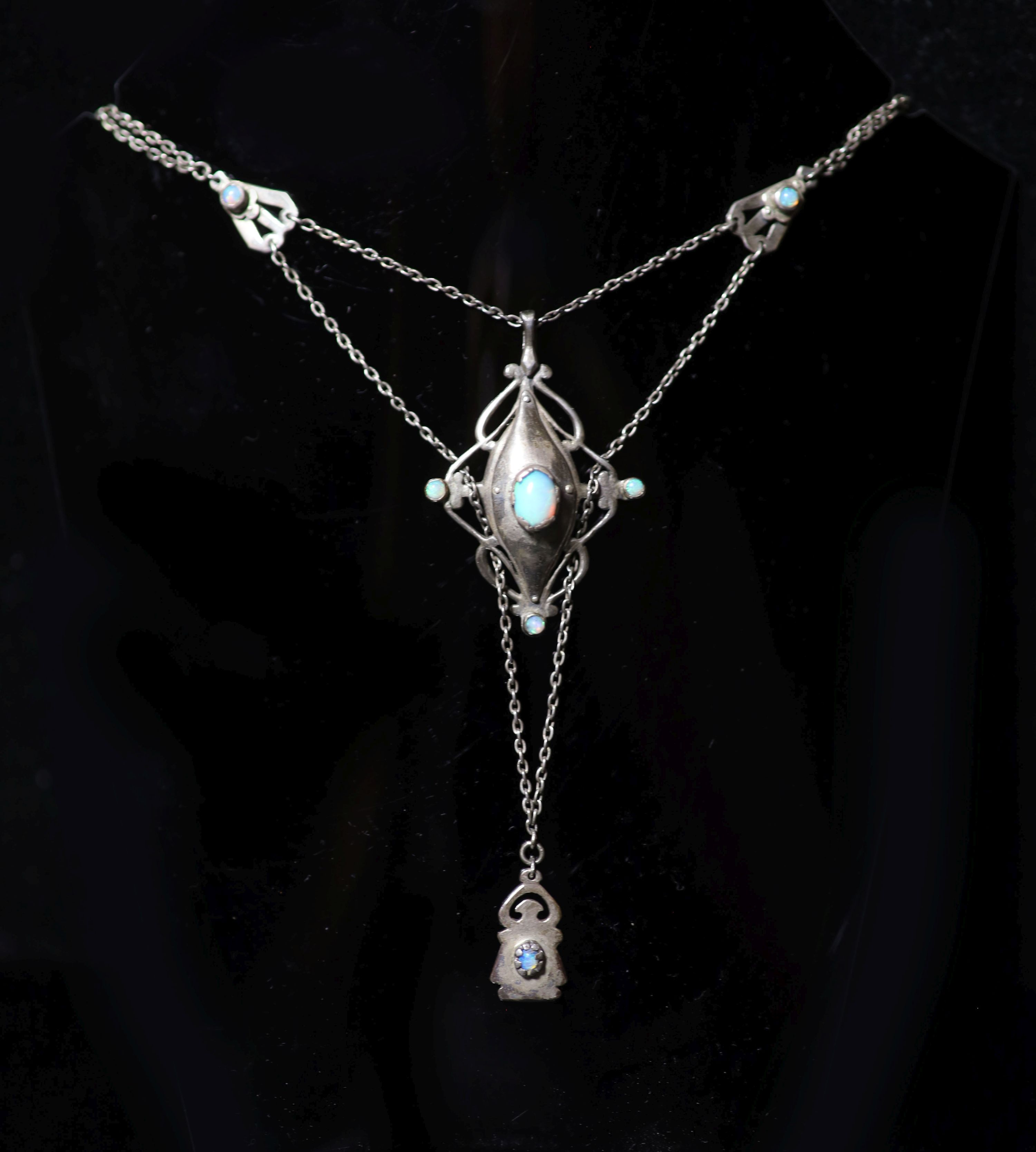 An early 20th century Arts & Crafts silver and nine stone cabochon black opal set drop pendant necklace